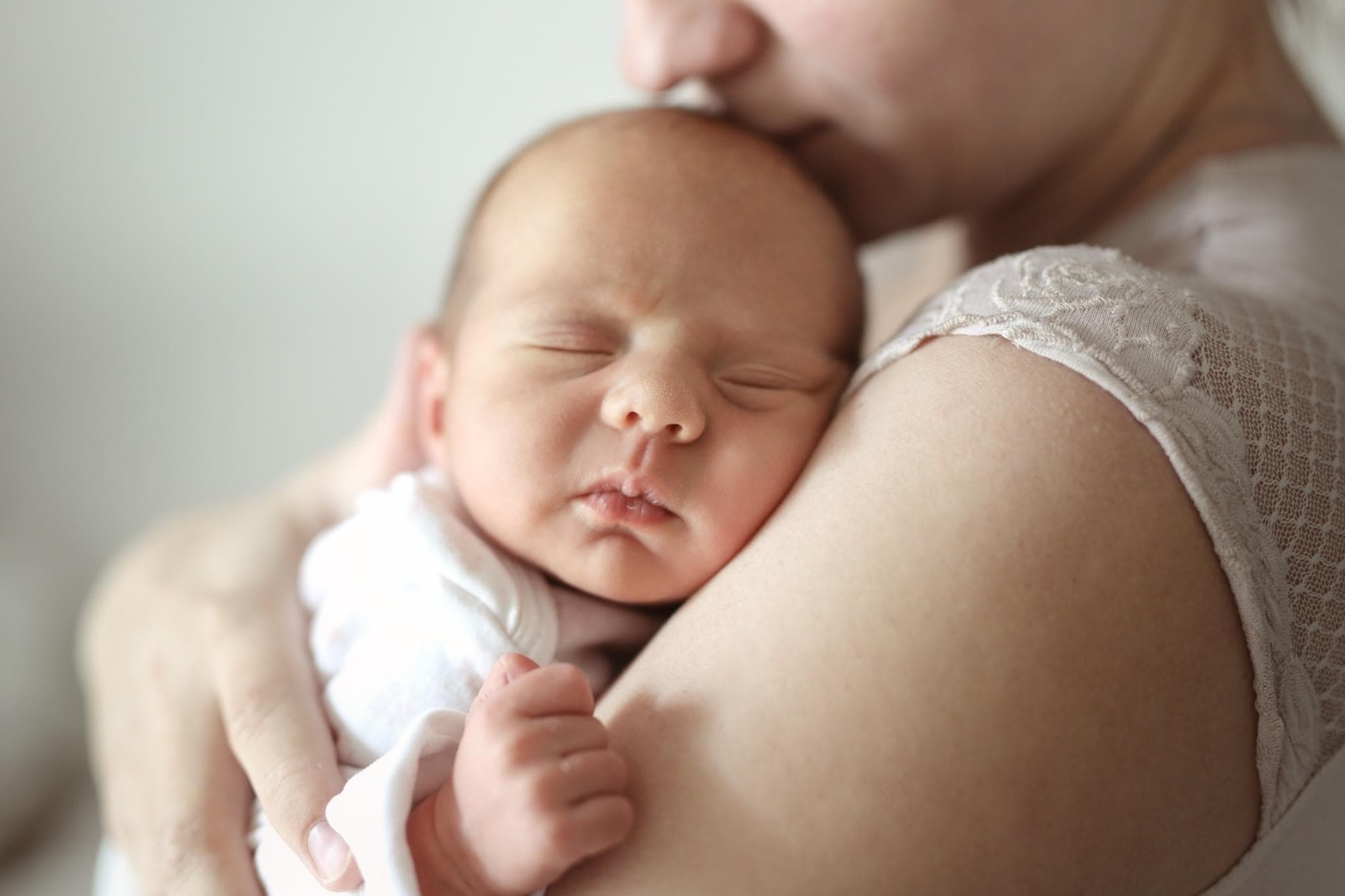 Mother kissing her newborn's head in a calm embrace